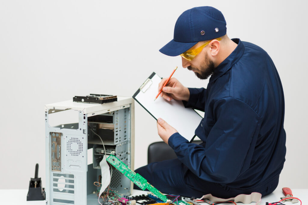 A man writing a notebook sitting beside an open PC. Concept image for how often one should cosider an upgrade for their gaming PC.