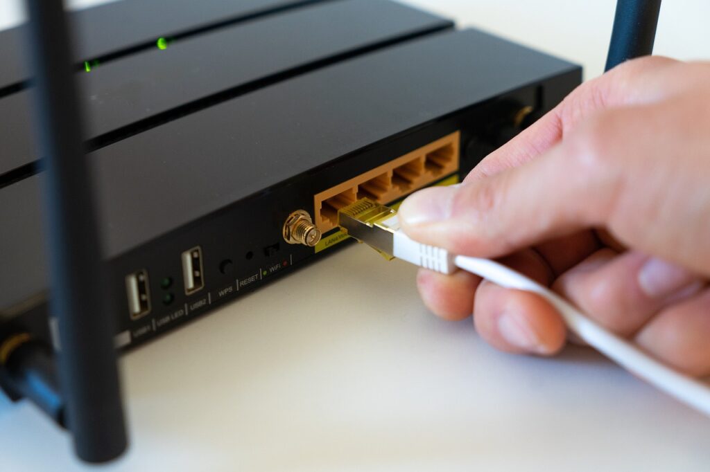 A person inserting an ethernet cable into a wifi-network router. Concept image for network accessibility of using an old gaming PC as a NAS device.