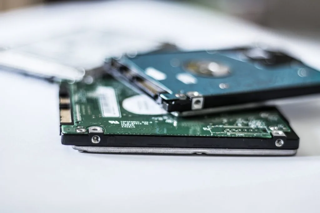 Two hard drive, one in black and other in blue, stack over one another over a table. Concept image for using a 500GB SSD along with an HDD for gaming.