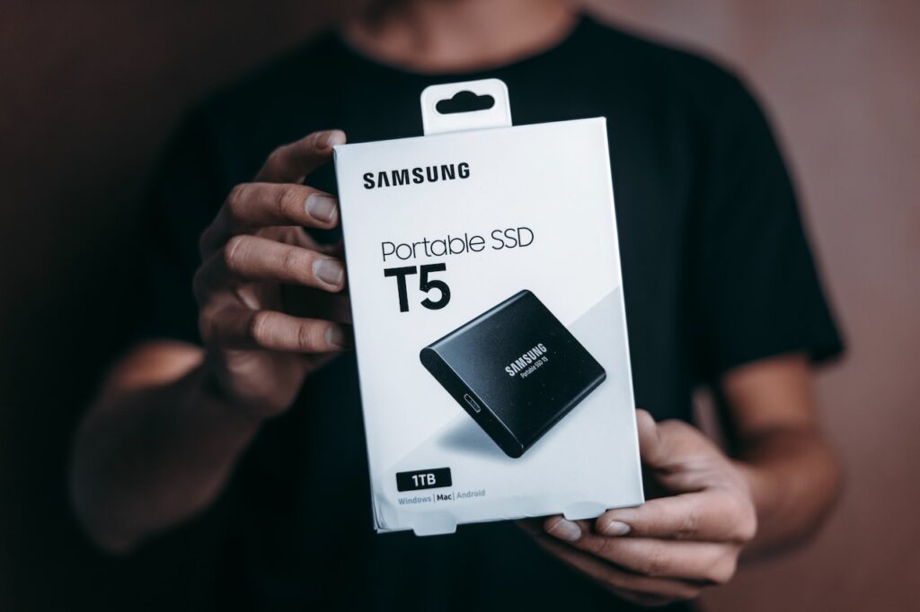 A man holding a box of a samsung portable 1TB SSD. Concept image for how 1TB SSD is better than 500GB SSD.