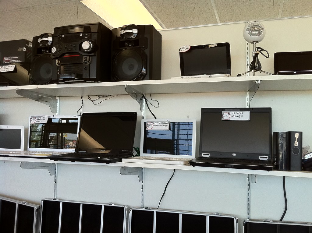 A shop having laptops placed on a display shelf. Concept image for why gaming laptops are cheaper than business laptops in some cases.