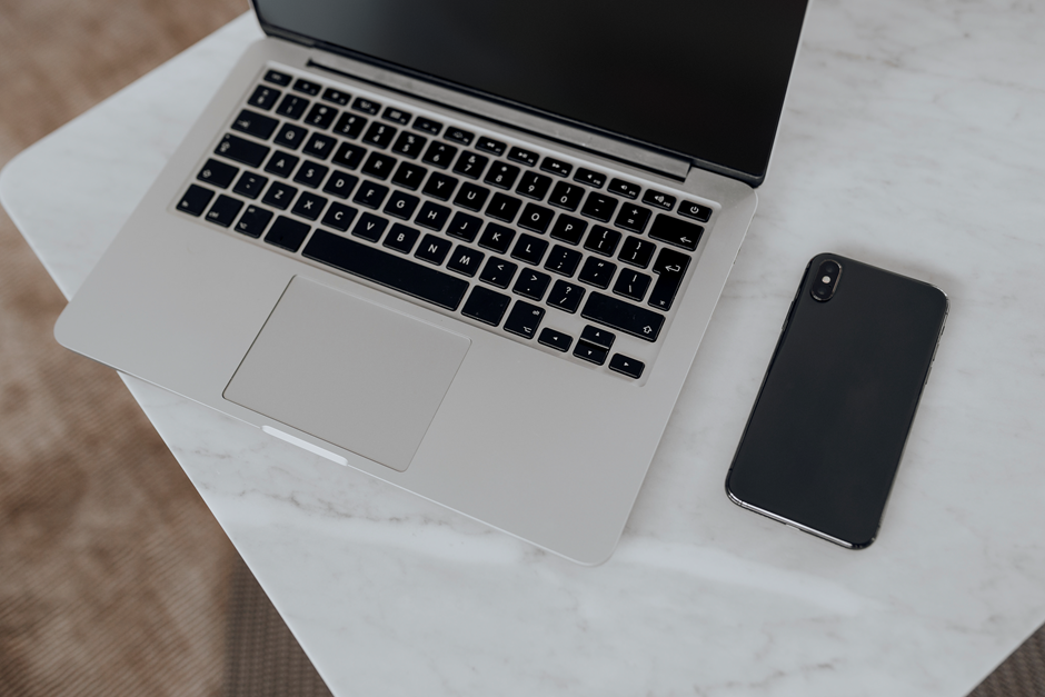 A macbook along with a mobile placed on a table use by a developer for game development.