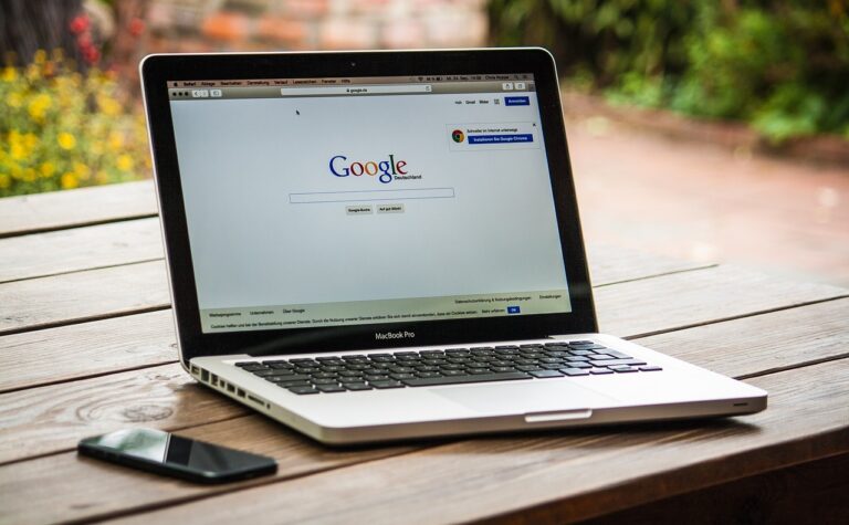 A laptop placed on a table along with a mobile phone.